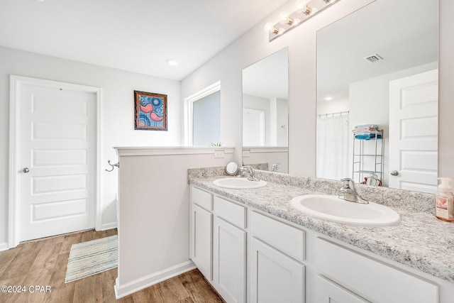 bathroom with dual vanity and wood-type flooring