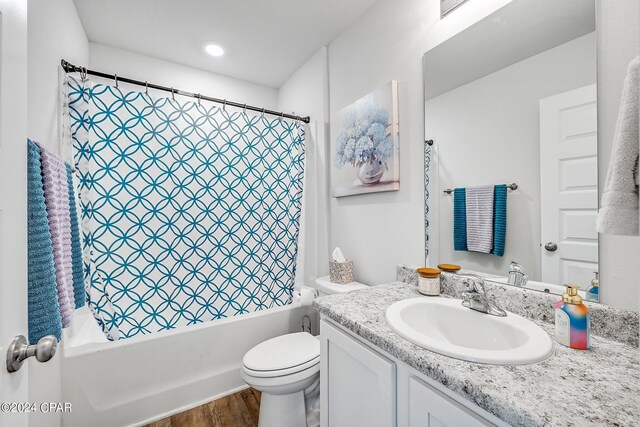 full bathroom featuring hardwood / wood-style flooring, toilet, shower / bathtub combination with curtain, and vanity