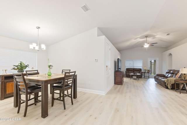 dining room with ceiling fan with notable chandelier, lofted ceiling, and light hardwood / wood-style floors