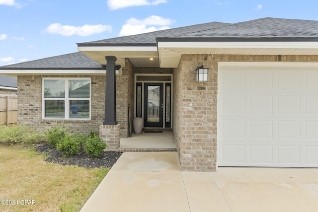 doorway to property with a garage, brick siding, and a shingled roof