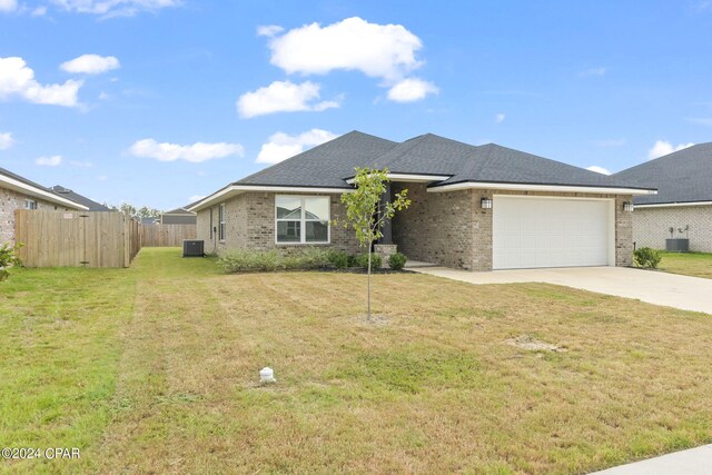 view of front of property featuring a garage, a front yard, and central AC