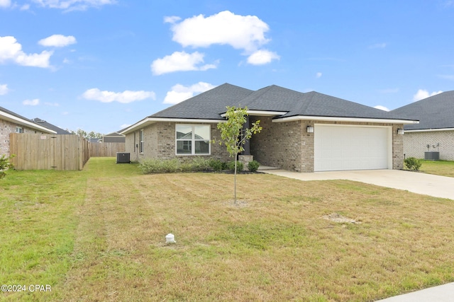 view of front of house with fence, driveway, an attached garage, a front lawn, and central air condition unit