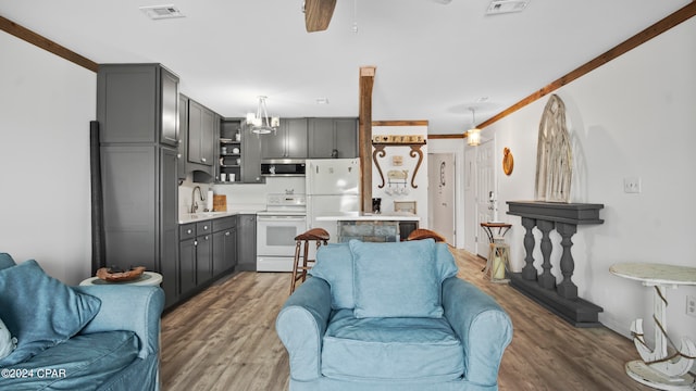 living room featuring sink, ceiling fan with notable chandelier, dark wood-type flooring, and ornamental molding