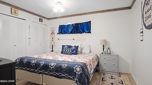 bedroom with light wood-type flooring, multiple closets, and ceiling fan