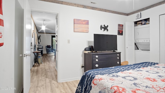 bedroom with stacked washer and clothes dryer and light hardwood / wood-style flooring