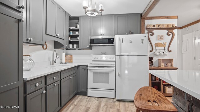 kitchen with gray cabinetry, white appliances, light hardwood / wood-style floors, and sink