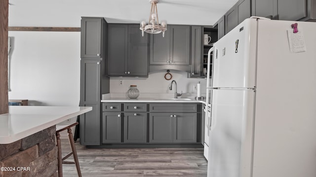 kitchen with sink, hardwood / wood-style flooring, white fridge, hanging light fixtures, and gray cabinets