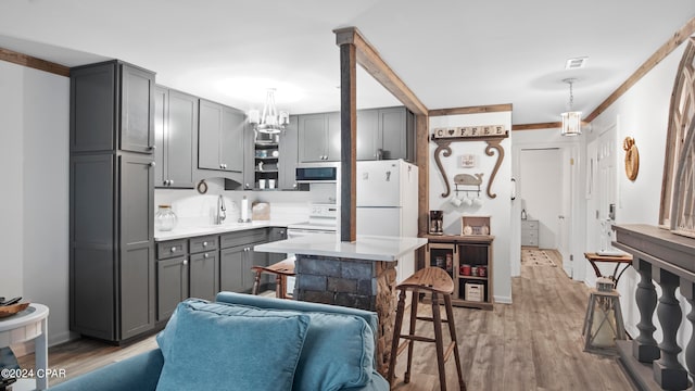 kitchen featuring white appliances, pendant lighting, gray cabinets, and light wood-type flooring