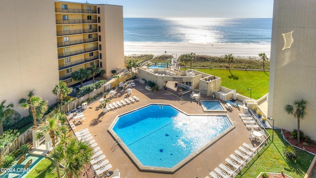 view of pool with a patio, a water view, and a beach view