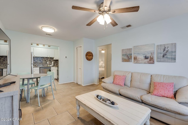 living area featuring ceiling fan, visible vents, baseboards, and light tile patterned flooring