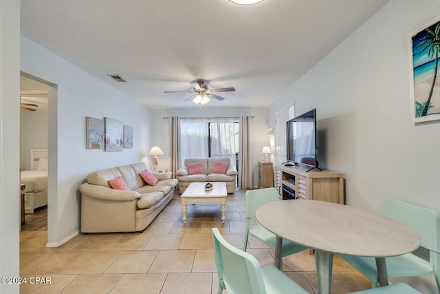 living area with visible vents, light tile patterned flooring, a ceiling fan, and baseboards