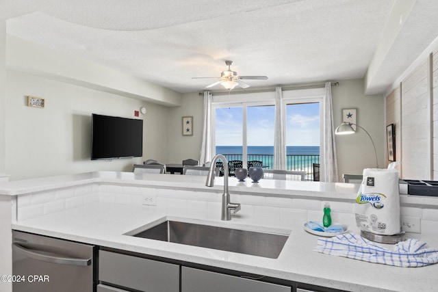 kitchen featuring ceiling fan, sink, a textured ceiling, and stainless steel dishwasher