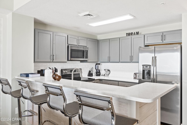 kitchen featuring kitchen peninsula, gray cabinets, and appliances with stainless steel finishes