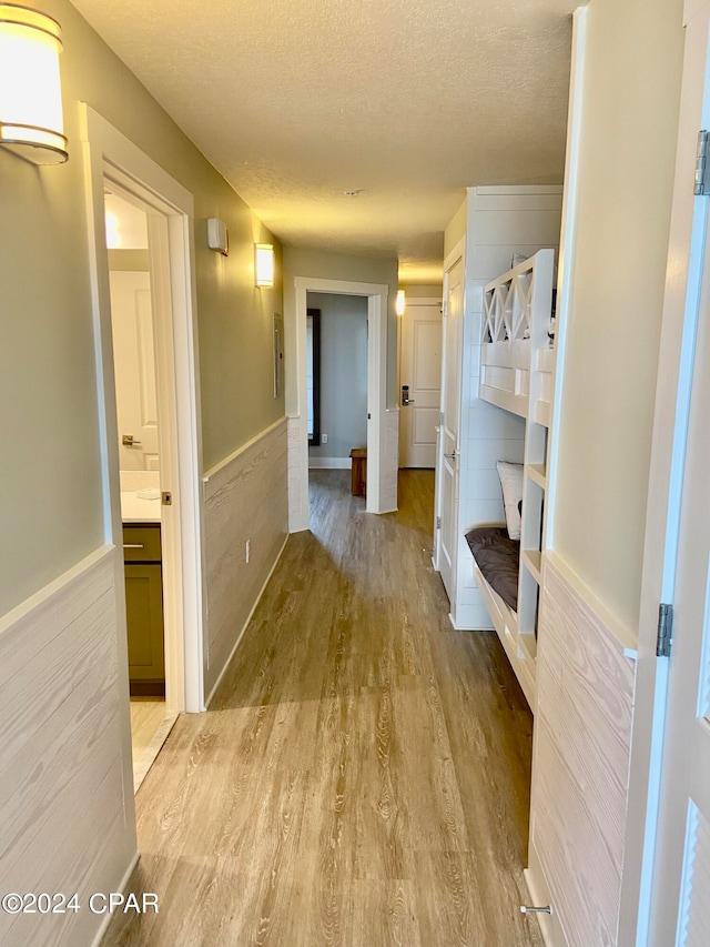 hallway featuring a textured ceiling and light hardwood / wood-style flooring