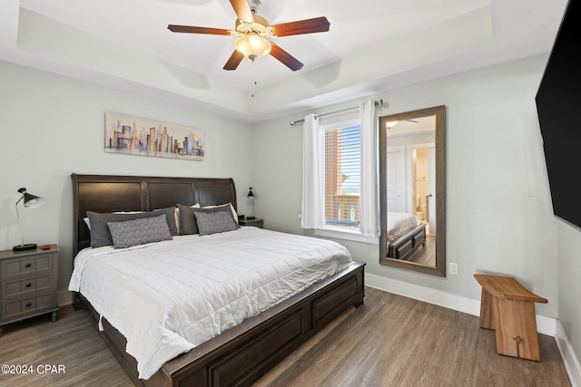 bedroom with a raised ceiling, hardwood / wood-style floors, and ceiling fan