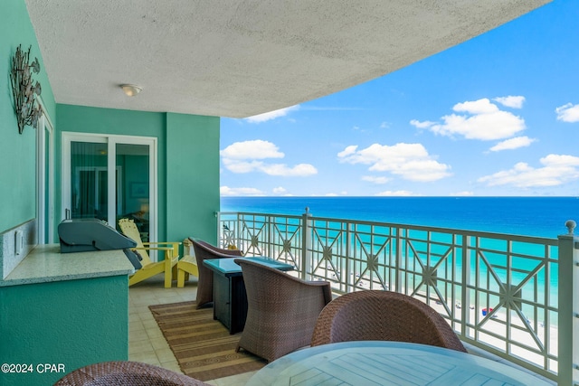 balcony featuring a view of the beach and a water view