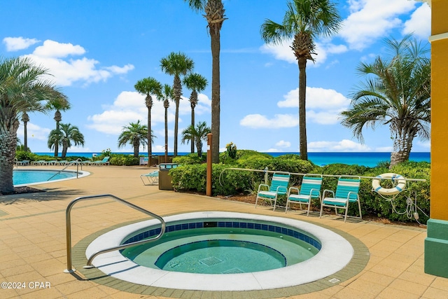 view of swimming pool featuring a water view, a patio area, and a community hot tub