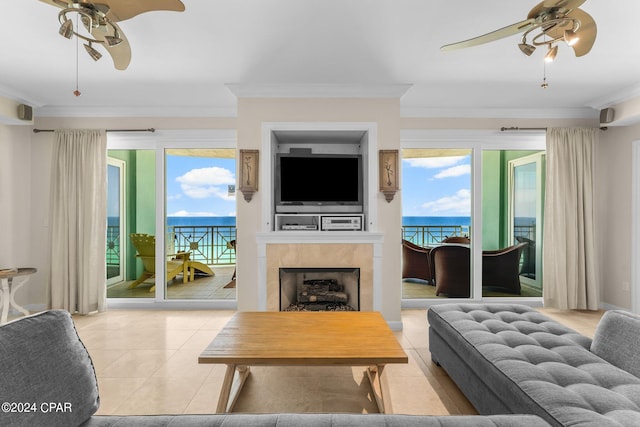 tiled living room featuring ceiling fan, a tile fireplace, and crown molding