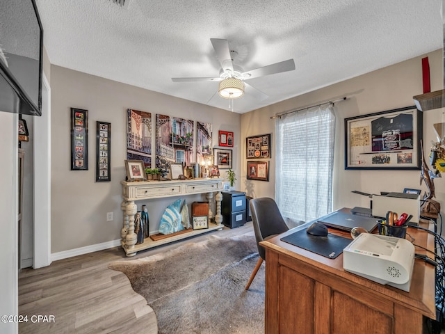 office area with a textured ceiling, light hardwood / wood-style floors, and ceiling fan