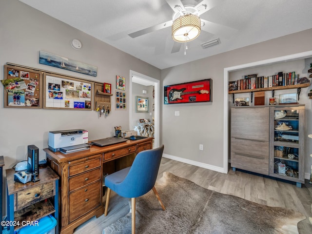 office featuring light wood-type flooring, a textured ceiling, and ceiling fan