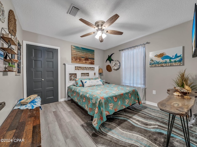 bedroom with ceiling fan, a textured ceiling, a closet, and light hardwood / wood-style flooring