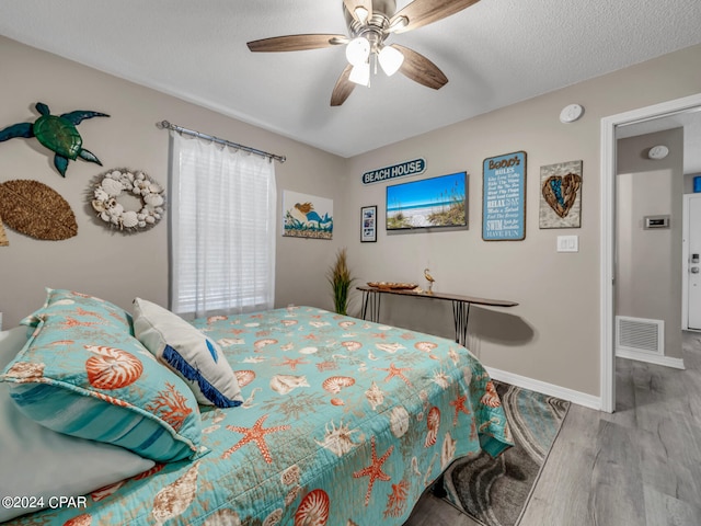 bedroom featuring light wood-type flooring, ceiling fan, and a textured ceiling