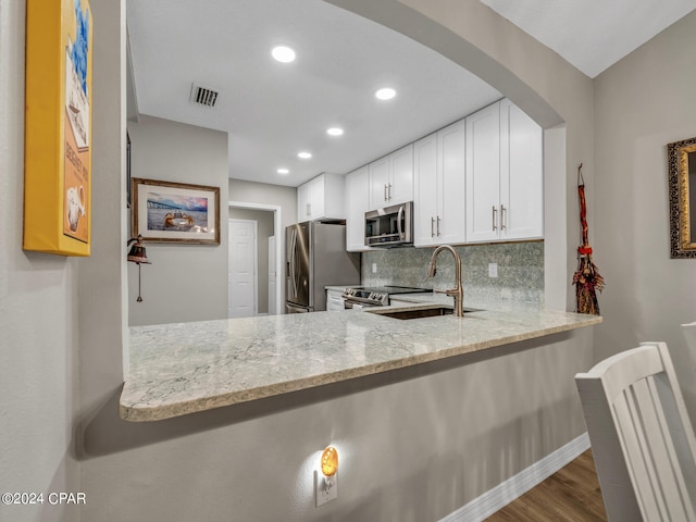 kitchen featuring white cabinets, sink, appliances with stainless steel finishes, light stone countertops, and decorative backsplash