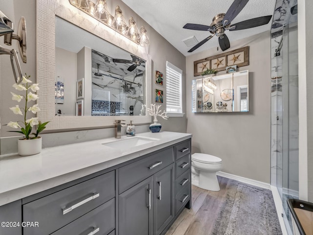 bathroom featuring a shower with door, hardwood / wood-style floors, ceiling fan, vanity, and toilet