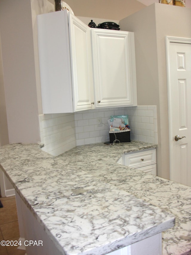 kitchen with light stone counters, white cabinetry, and decorative backsplash