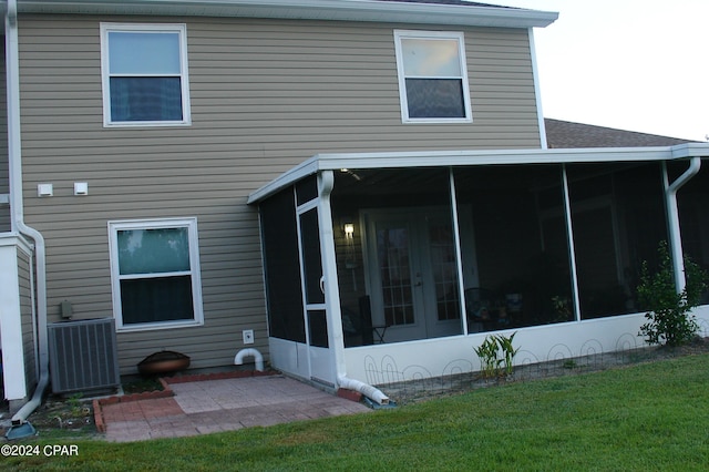 rear view of house with central AC unit, a sunroom, and a yard