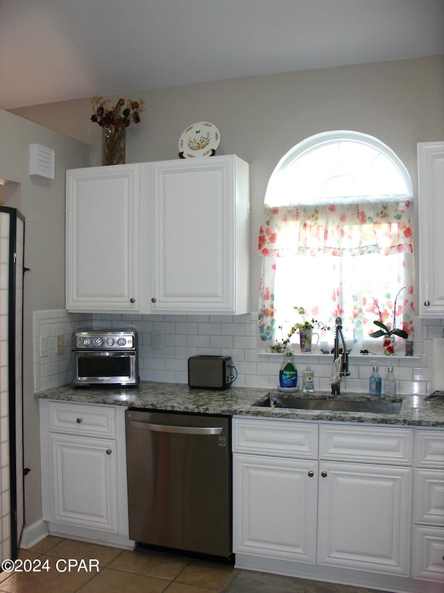 kitchen featuring white cabinetry, decorative backsplash, tile patterned flooring, stainless steel dishwasher, and sink