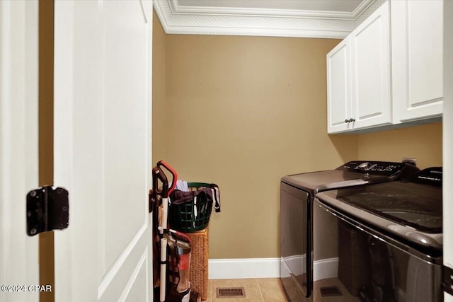 laundry area with light tile patterned flooring, washer and dryer, crown molding, and cabinets