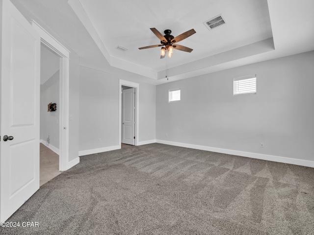 carpeted empty room featuring a tray ceiling and ceiling fan