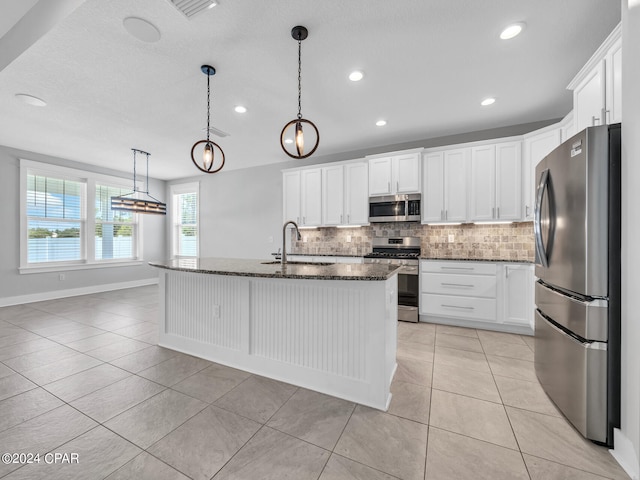 kitchen with appliances with stainless steel finishes, white cabinetry, a kitchen island with sink, and sink