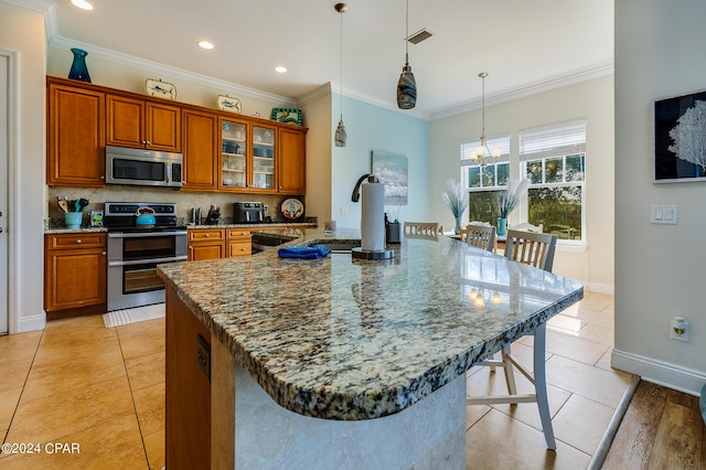 kitchen with stainless steel appliances, decorative light fixtures, a large island with sink, sink, and a kitchen breakfast bar