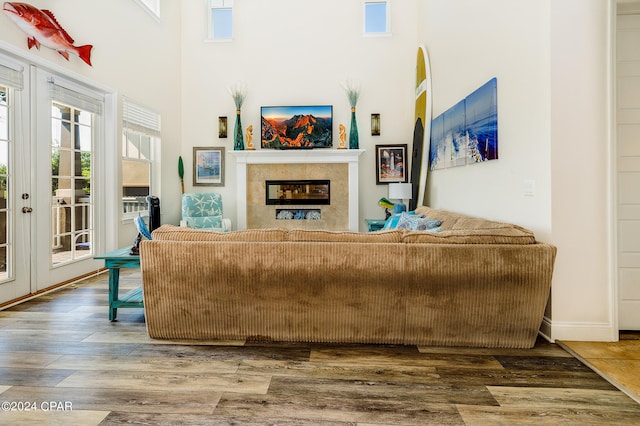 living room with french doors, a towering ceiling, and hardwood / wood-style floors