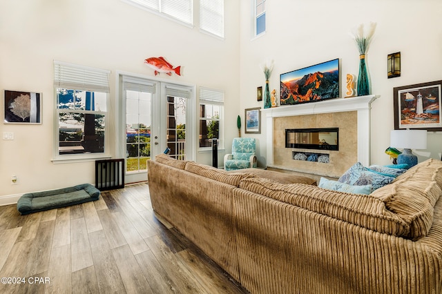 living room featuring french doors, wood-type flooring, a high ceiling, and a fireplace