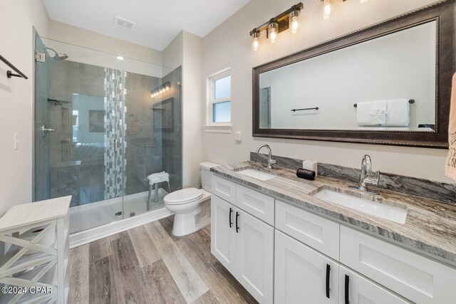 bathroom featuring an enclosed shower, toilet, dual vanity, and wood-type flooring