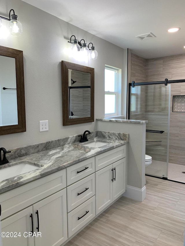 bathroom featuring a shower with door, vanity, toilet, and wood-type flooring