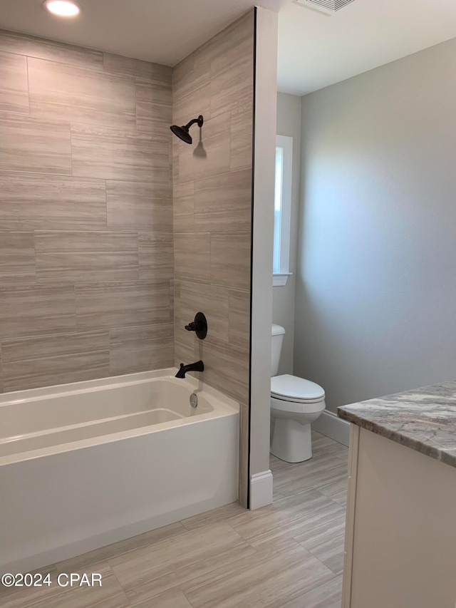 full bathroom with tiled shower / bath, vanity, and toilet