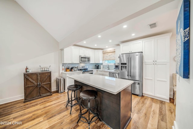 kitchen with a center island, stainless steel appliances, a breakfast bar, and white cabinets