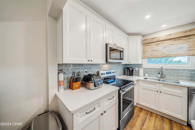 kitchen featuring appliances with stainless steel finishes, sink, decorative backsplash, and white cabinets