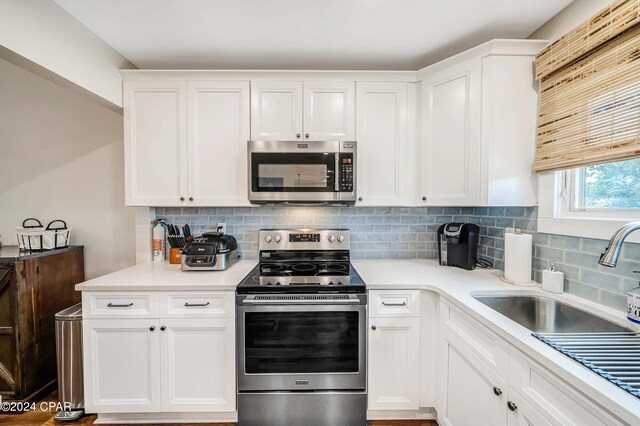 kitchen featuring light wood-type flooring, sink, white cabinetry, decorative backsplash, and stainless steel appliances