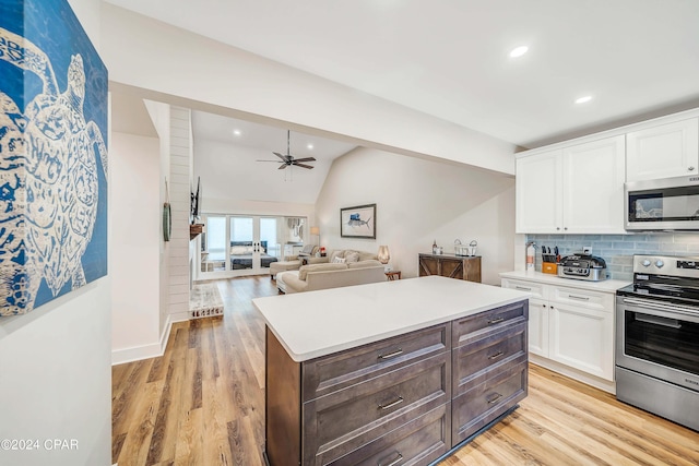 kitchen with stainless steel appliances, a center island, white cabinets, and light wood-type flooring