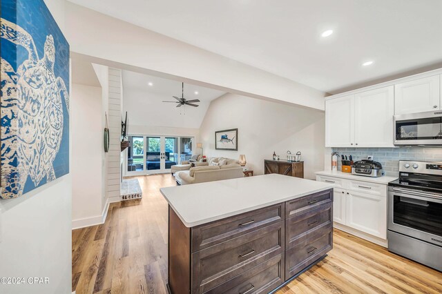 kitchen with ceiling fan, white cabinetry, stainless steel appliances, light wood-type flooring, and vaulted ceiling