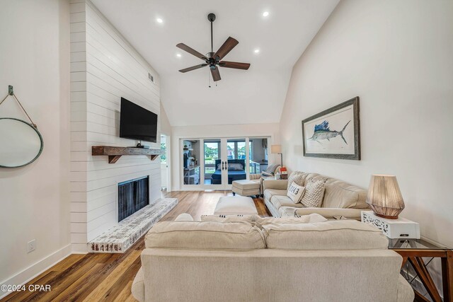 living room with ceiling fan, french doors, high vaulted ceiling, a large fireplace, and hardwood / wood-style floors