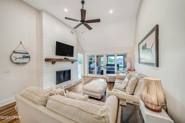 living room featuring a high ceiling, wood-type flooring, a large fireplace, and ceiling fan