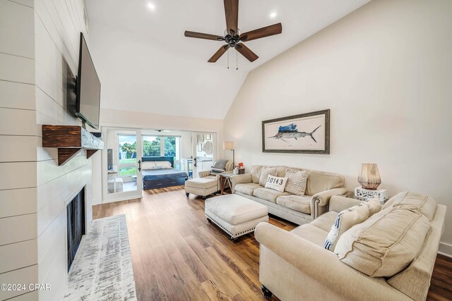 living room featuring high vaulted ceiling, a fireplace, wood-type flooring, ceiling fan, and french doors