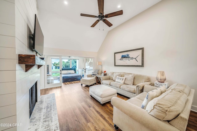 living room featuring a fireplace, wood-type flooring, high vaulted ceiling, and ceiling fan