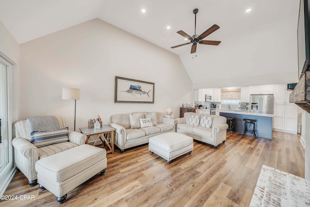 living room featuring light hardwood / wood-style flooring, high vaulted ceiling, and ceiling fan